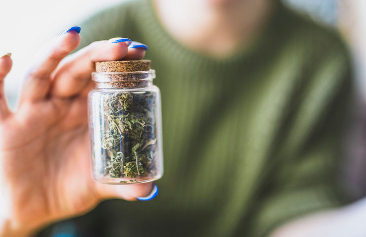Woman holding a jar filled with marijuana
