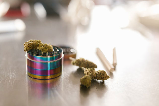 Cannabis pre-rolls next to a grinder
