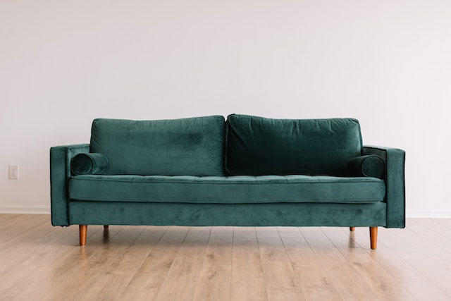 Green couch on wooden floor