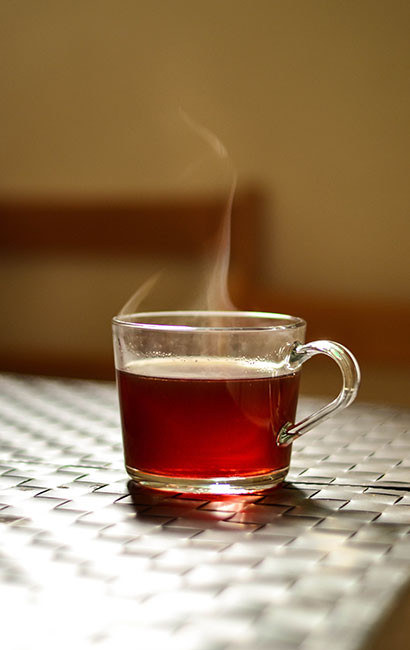 A glass cup filled with hot tea and steam coming out