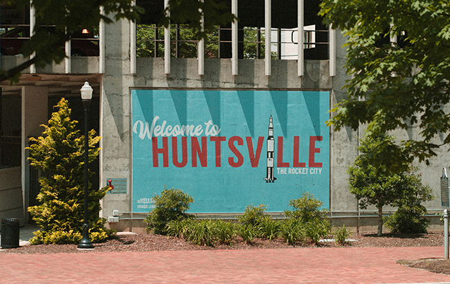 Building with a painted "Welcome to Huntsville" sign on it surrounded by trees