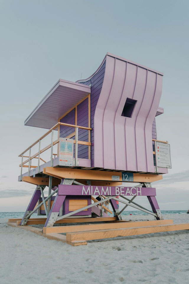  A white and purple lifeguard station on the beach during the early morning. 