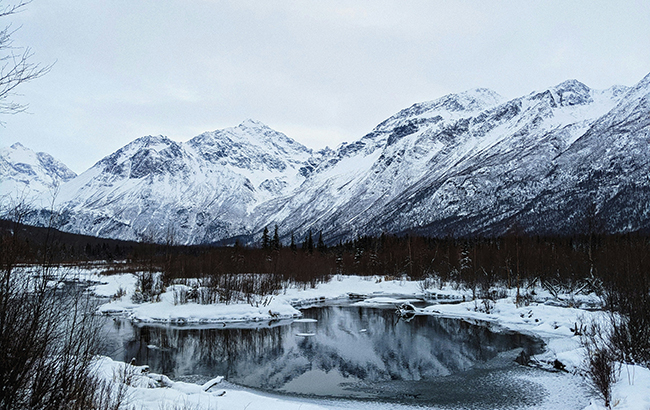 A lake in Anchorage that is surrounded by snow and mountains